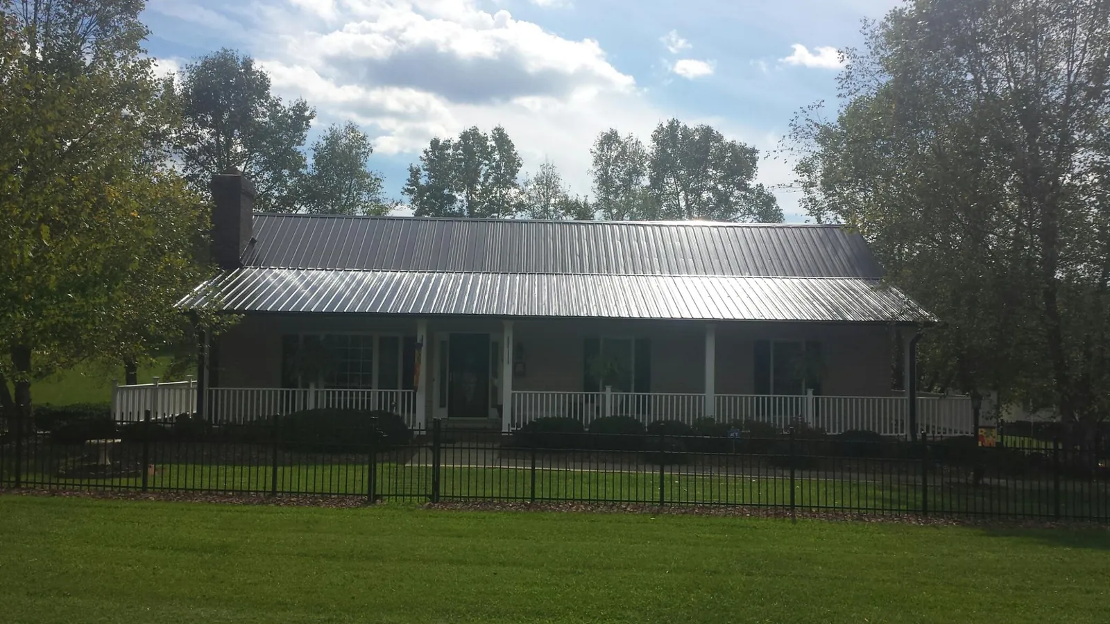 Gray metal roof on a brick ranch with a full width front porch — Gutter Guard Installation work by our crew in North Tonawanda
