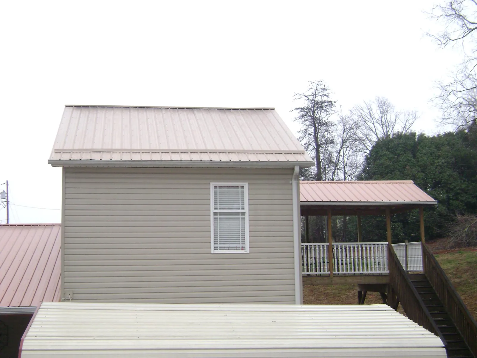 Tan metal roofs on a two story addition and attached porch, from a Roof Replacement job in North Tonawanda