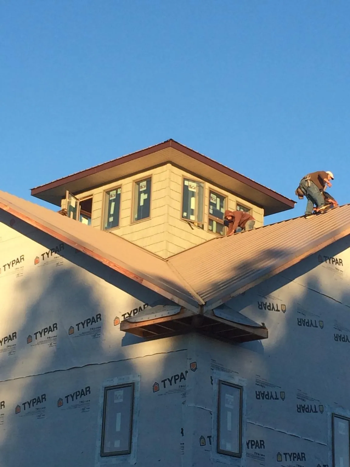 Roofers working around a rooftop cupola on a new metal roof at sunset — Roof Waterproofing in North Tonawanda by Roofing Brothers